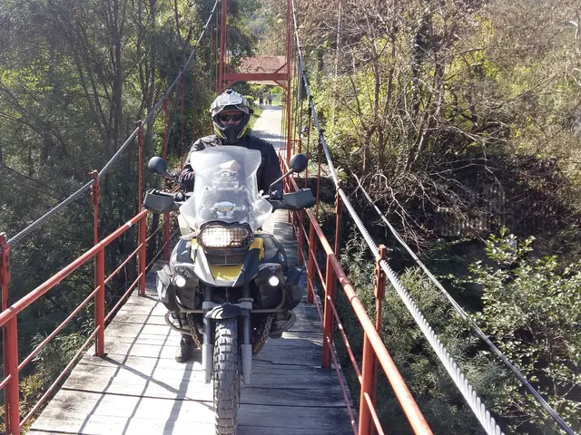 Motorkář na motorce přejíždí dřevěný most.