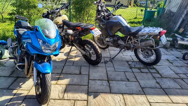 Motoservis: Tři zaparkované motocykly na dlážděném dvoře