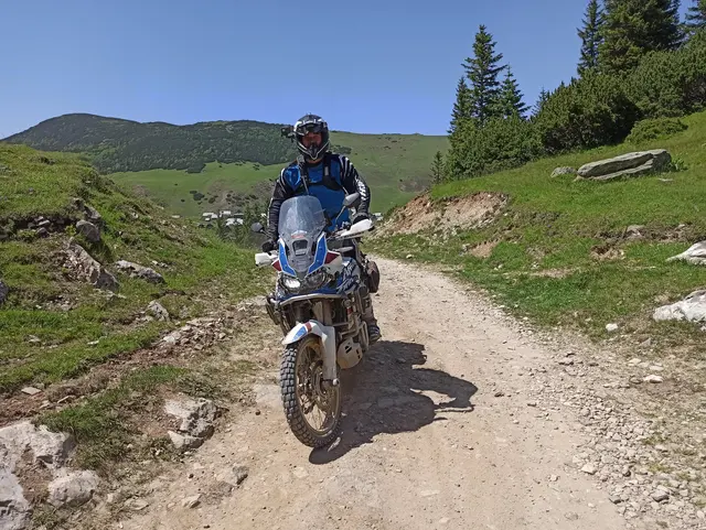 Jezdec na enduro motorce na prašné cestě v horách.