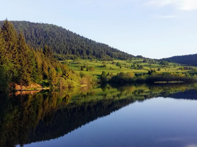 Jarní výprava Bosna: jezero odráží zelené kopce.